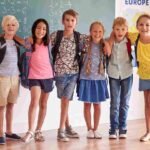 A group of six smiling students standing together in a classroom in front of a chalkboard with math equations.