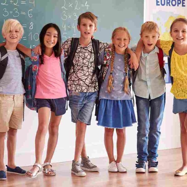 A group of six smiling students standing together in a classroom in front of a chalkboard with math equations.