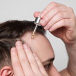 Man applying serum to scalp